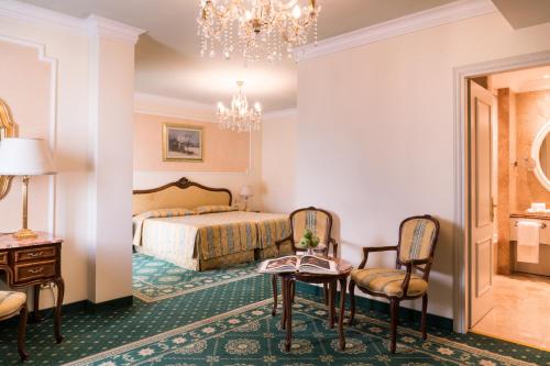 a hotel room with a bed and a chandelier at Abano Grand Hotel - Lifestyle Spa & Fine Dining in Abano Terme