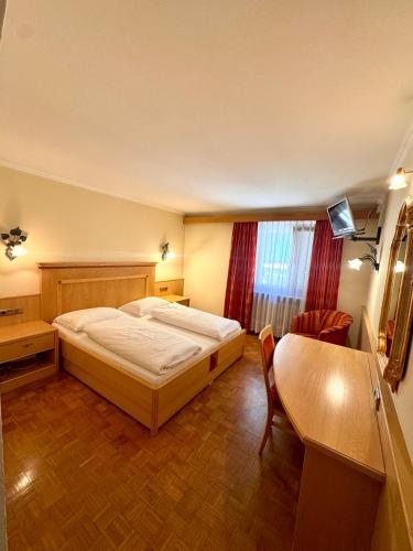 a bedroom with a bed and a table and a chair at Hotel Goldenes Kreuz - since 1605 in Vipiteno
