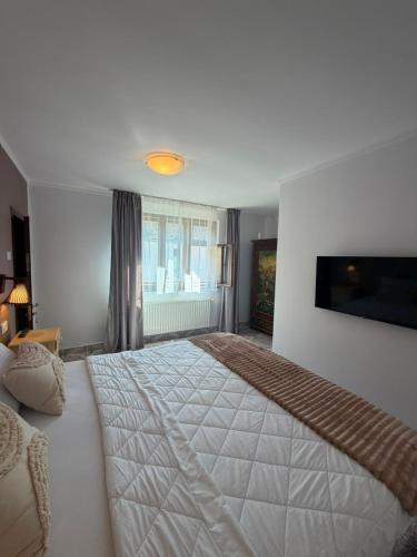 a bedroom with a large white bed in a room at La umbra nucului bătrân in Ghimbav