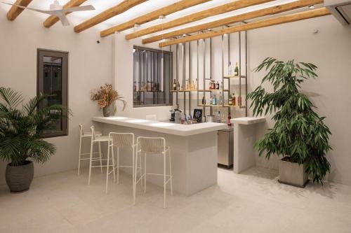 a kitchen with a bar with stools and plants at Anapollo Boutique Hotel Adults Only in Naxos Chora