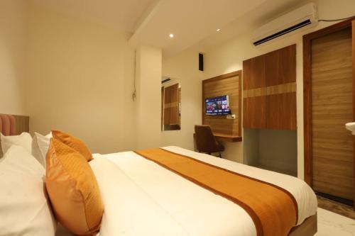 a bedroom with a large bed and a television at Yu Hotel in Kānpur
