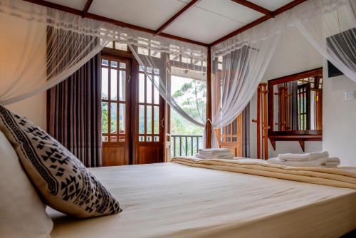 a bedroom with a bed with curtains and a window at MOUNT PLEASANT ELLA in Ella