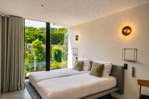 two beds in a room with a large window at K-Kanne in Kanne