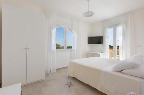 a white bedroom with a bed and a window at B&B Li Peticurti in Cerfignano