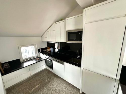 a kitchen with white cabinets and black appliances at Modern Penthouse with Unbeatable Panoramic Views in Peje