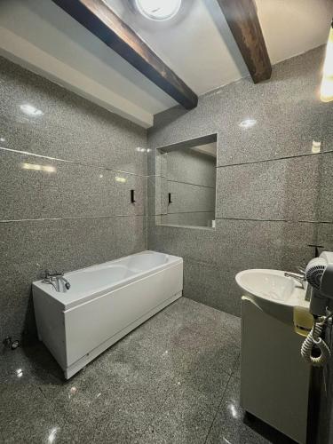 a bathroom with a bath tub and a sink at Hotel Bran Dracula in Bran