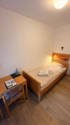 a small bedroom with a bed and a table at Haus Mariengrund in Münster