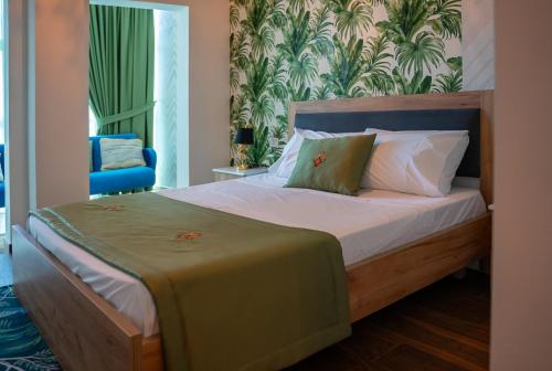 a bedroom with a bed with a green blanket on it at N'Log N'Skuraj Hotel in Ferr -Skuraj
