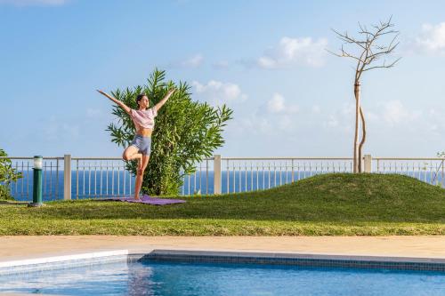 a woman jumping in the air next to a swimming pool at Baía II by An Island Apart in Funchal
