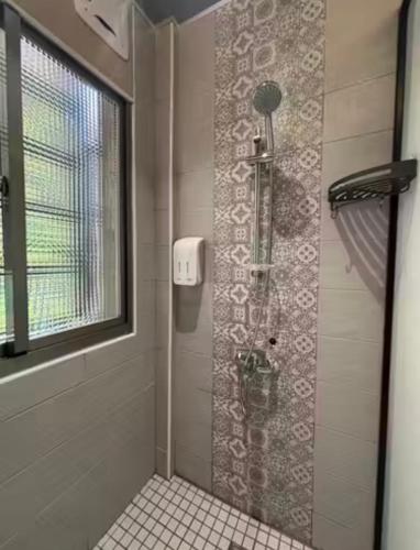a shower in a bathroom with a window at Moon Homestay in Jincheng