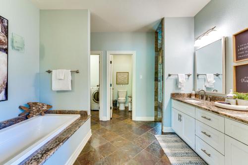 a bathroom with a tub and two sinks and a toilet at 4-Season Boathouse, Hot Tub! Guadalupe River Oasis in Seguin