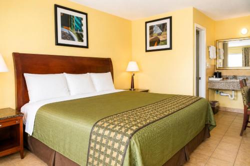 a hotel room with a bed with a green bedspread at Great Western Inn Pasadena in Pasadena
