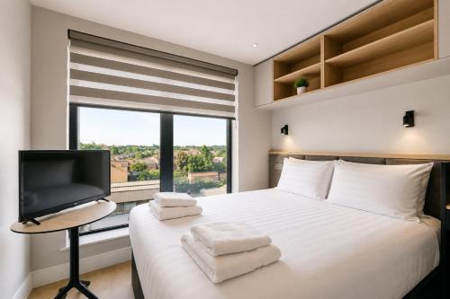 a bedroom with a bed with a tv and a window at Argyl - The Apiary, Ealing in Ealing