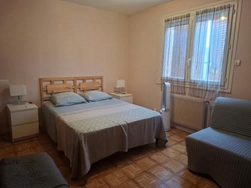 a bedroom with a bed and a chair and two windows at LA BOUVIERE in Aulnat