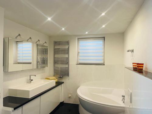 a white bathroom with a tub and a sink at Blick ins Grüne in Daisendorf