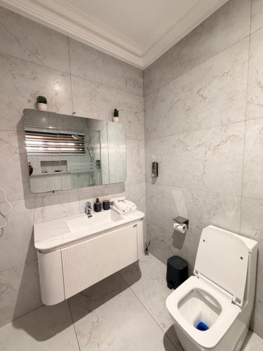 a white bathroom with a toilet and a sink at Sonia Hotel in Accra