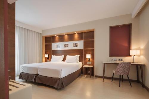 a hotel room with a large bed and a desk at Dorma León in León