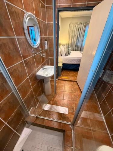 a small bathroom with a sink and a mirror at Marion Lodge in Johannesburg
