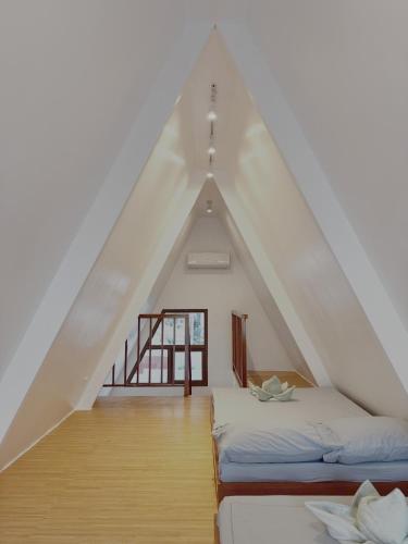 a attic room with two beds and a window at Balay @ Santa Fe, Bantayan in Pooc