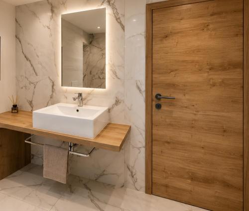 a bathroom with a sink and a wooden door at Apartma 47 in Kobarid