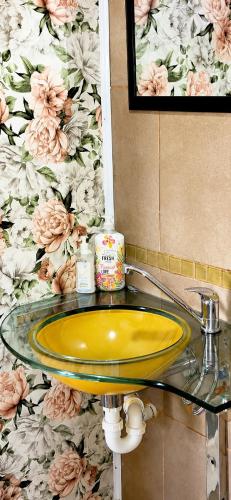 a yellow sink in a bathroom with floral wallpaper at Peacock Cove Self Catering Studio in Gordonʼs Bay