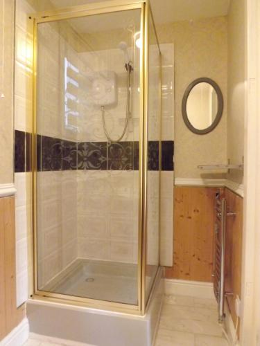 a shower with a glass door in a bathroom at Small cosy bothy in Dingwall