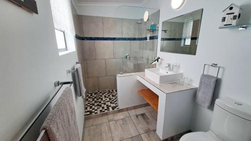 a white bathroom with a sink and a shower at Avenues Guesthouse in Mossel Bay