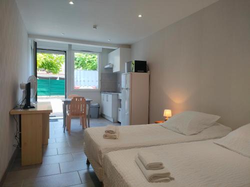 a bedroom with two beds and a desk with a television at Locaplage in Lanton