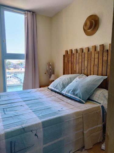 a bedroom with a bed with a wooden headboard and a window at La Terrasse des Voiliers in Frontignan