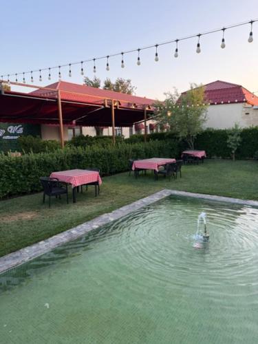 a pool of water in a yard with picnic tables at Very Well Guest House in Baku