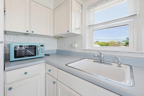 a white kitchen with a microwave and a sink at Beach Home With Beautiful Ocean Views in Dennis