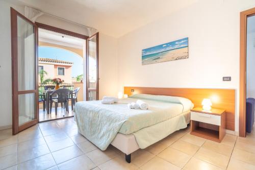 a bedroom with a bed and a balcony with a table at Residence Le Fontane in Villasimius