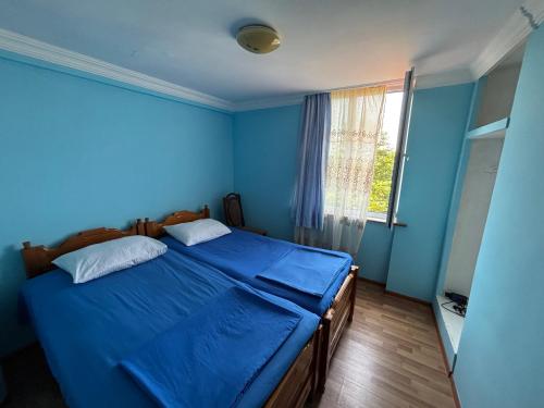 a blue bedroom with a bed with blue sheets and a window at Beka's GuestHouse in Gonio