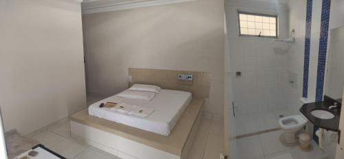 a small white bathroom with a bed and a shower at Motel Classe A in Limeira
