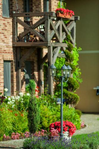 a street light in a garden with flowers in front of a building at Villa Mare Apartamenty in Grzybowo