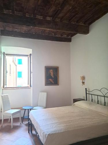 ein Schlafzimmer mit einem Bett, zwei Stühlen und einem Fenster in der Unterkunft Nerucci 3 in Castel del Piano