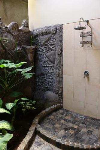a bathroom with a shower with a stone wall at Lovina Beachhouse Villas in Lovina