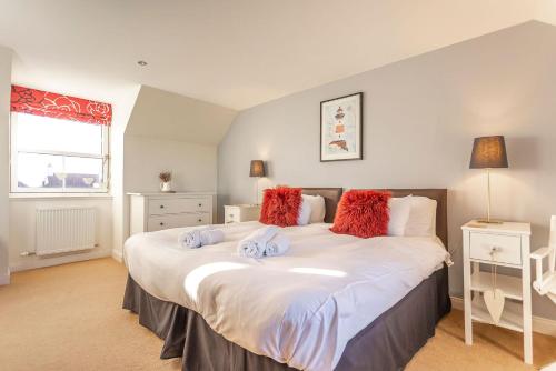 a bedroom with a large white bed with red pillows at Links Lodge - Blacklaws Steading in Anstruther