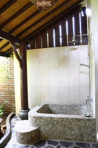 a bath tub with a shower in a room at Lovina Beachhouse Villas in Lovina