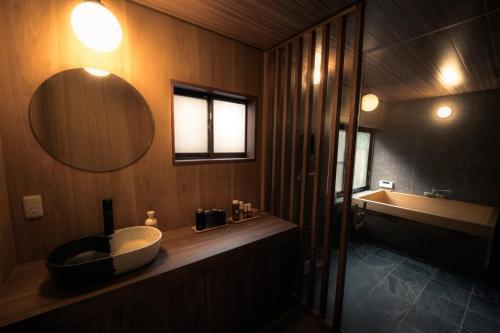 a bathroom with a sink and a tub and a mirror at 福渡邸 in Narita