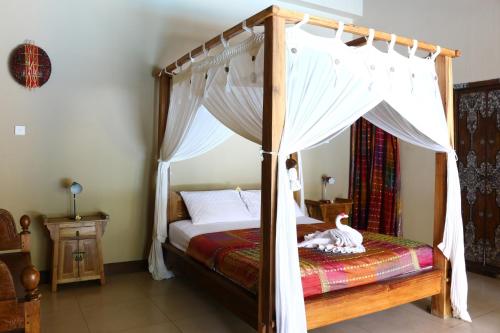 a bedroom with a canopy bed with a swan on it at Lovina Beachhouse Villas in Lovina