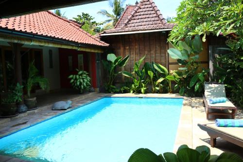 a swimming pool in front of a house at Lovina Beachhouse Villas in Lovina