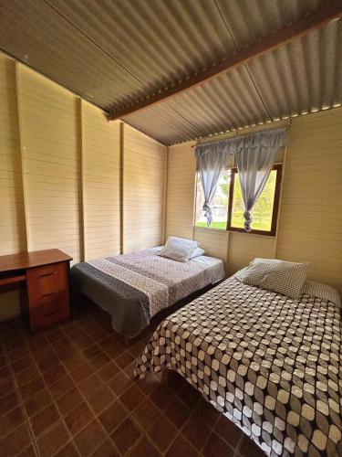 a bedroom with two beds and a desk and two windows at Cabaña de campo privada con piscina in Casa Blanca Hacienda
