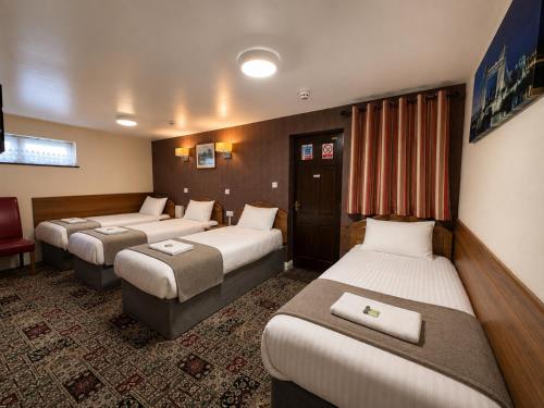 a hotel room with three beds and a chair at Twickenham Guest House in Twickenham
