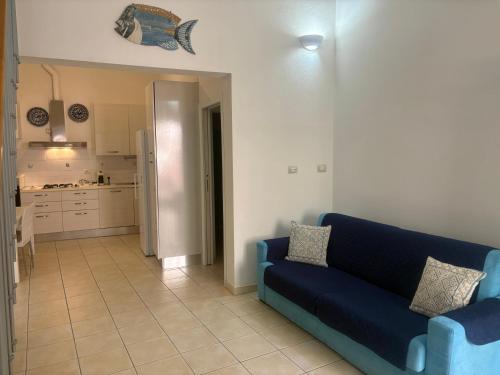 a living room with a blue couch and a kitchen at Casa Mare Teulada Sardegna in Teulada