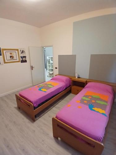 two beds in a room with purple sheets at B&B Angelo Azzurro in Carpi