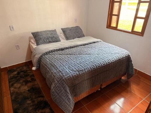 a bedroom with a bed with a blue comforter and a window at Cabanas Belvedere in Lauro Müller