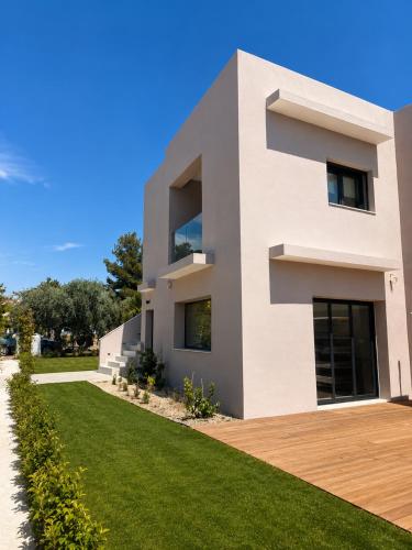 a white house with a green lawn at Minimal Suites in Skala Rachoniou