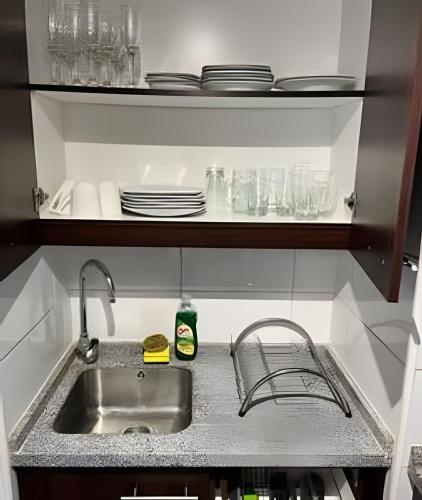 a kitchen sink with plates and dishes on a shelf at Departamento en Calama in Calama