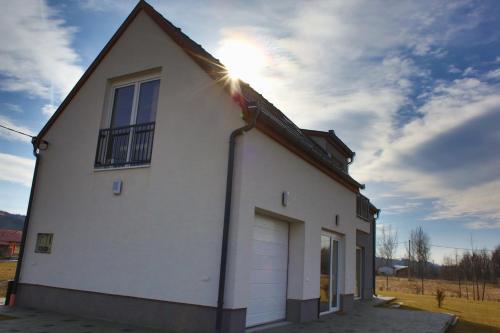 a white house with the sun shining on it at Szabolcs Apartments in Demjén